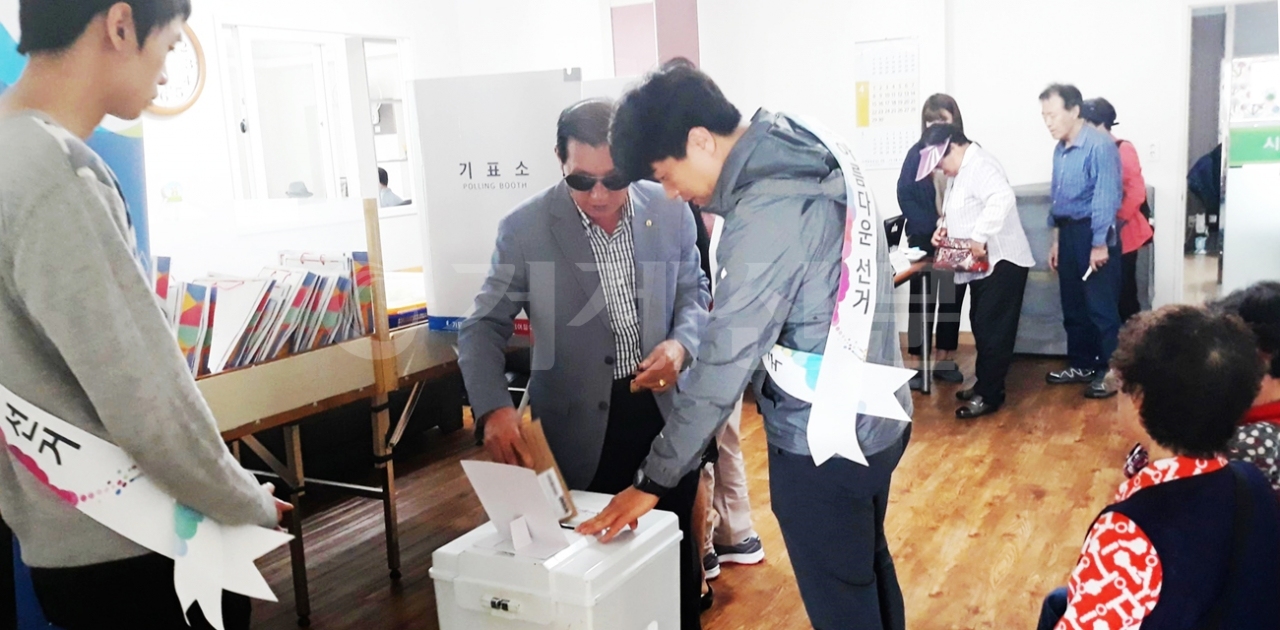 경남시각장애인복지연합회거제지회 회원들이 도움을 받아 모의 투표체험을 하고 있다.