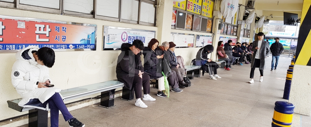 고현시외버스터미널 순환버스 대기소 온열의자에 앉아 버스를 기다리는 시민들 모습.