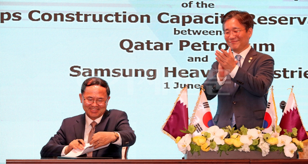 남준우 삼성중공업 사장(왼쪽)이 성윤모 산업통상자원부 장관의 축하를 받으며 LNG선 슬롯 예약 약정서에 서명하고 있는 모습.